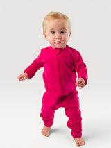 Iksplor baby wearing a vibrant pink merino wool zip romper with long sleeves and snug cuffs on a white background #color_peak pink