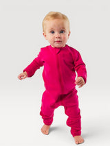 Iksplor baby wearing a vibrant pink merino wool zip romper with long sleeves and snug cuffs on a white background #color_peak pink