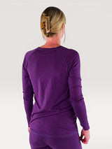 Back view of a woman wearing an Iksplor purple merino wool long sleeve nursing top with thumb holes. #color_huck-it-berry