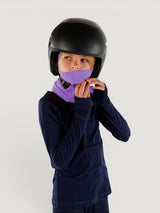Child wearing an Iksplor purple merino wool balaclava with a ponytail hole under a black ski helmet #color_lilac