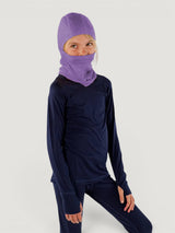 Child wearing a purple Iksplor merino wool balaclava with a ponytail hole and a matching navy blue base layer set. #color_lilac
