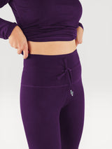 Iksplor deep purple merino wool baselayer leggings with a high-waisted drawstring fit on a woman #color_huck-it-berry