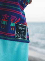 Iksplor x SURreal towel poncho featuring a blue patterned fabric with a collaborative brand patch at the beach #color_high tide
