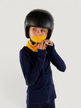 Child wearing a yellow Iksplor merino wool balaclava with a ponytail hole under a black ski helmet #color_yellowstone
