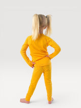 Child wearing bright yellow Iksplor merino wool base layer leggings and matching long sleeve top, back view #color_yellowstone