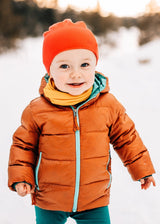 Toddler wearing an Iksplor yellow merino wool neck gaiter with a puffer jacket in a snowy outdoor setting #color_yellowstone